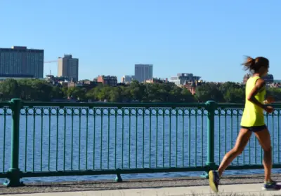 Woman running down the street next to a river overlook