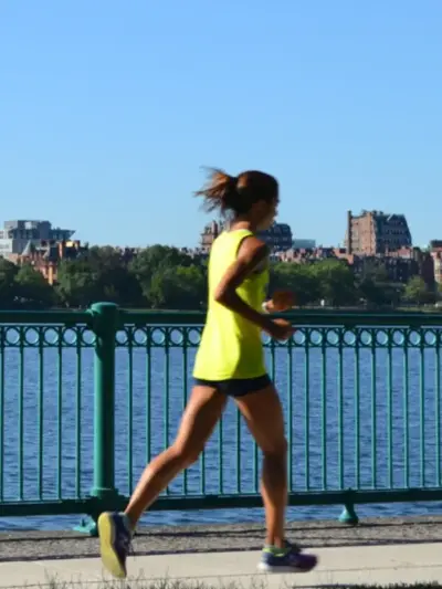 Woman running down the street next to a river overlook