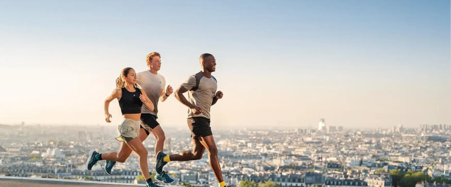 Group of two men and a woman running in Asics running shoes