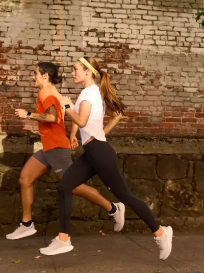 Man and woman running on a street in a pair of HOKA running shoes