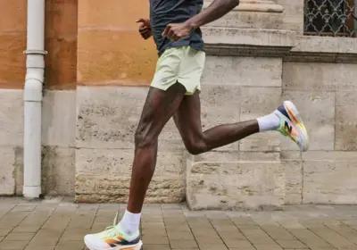 Man running along a sidewalk while wearing a pair of New Balance running shoes