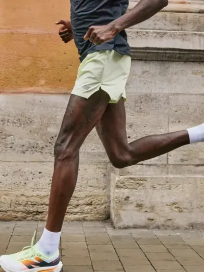 Man running along a sidewalk while wearing a pair of New Balance running shoes