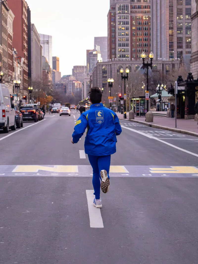 runner crossing boston marathon finish line in adidas baa jacket